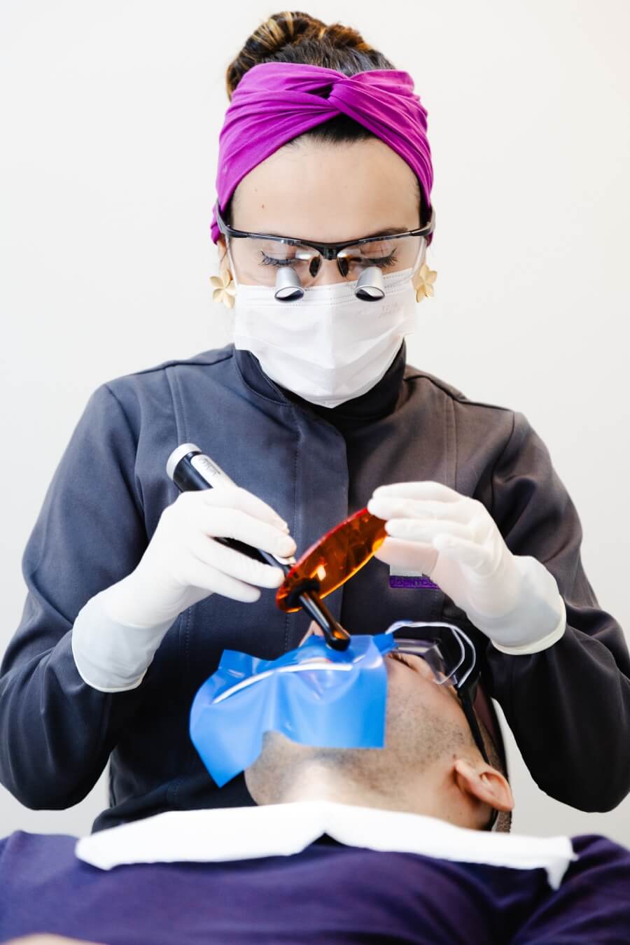 Dentista utilizando fotopolimerizador para clareamento dental a laser em paciente. Especialista na Vila Clementino na clínica RM Odontologia Integrativa.