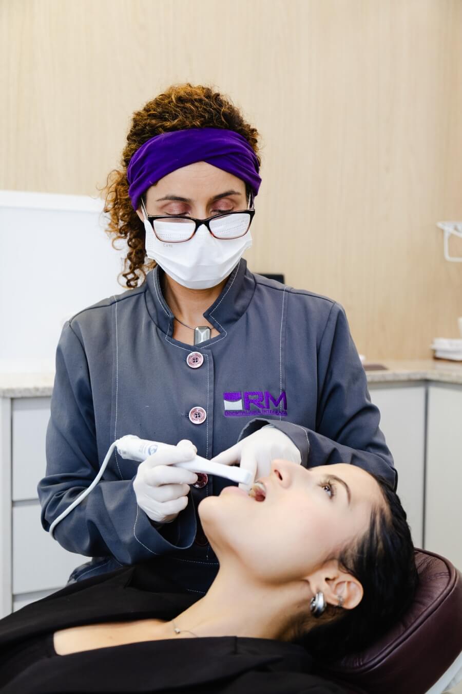 Dentista utilizando scanner intraoral para planejamento de lentes de contato dental em paciente. Tecnologia estética na Vila Clementino na RM Odontologia.