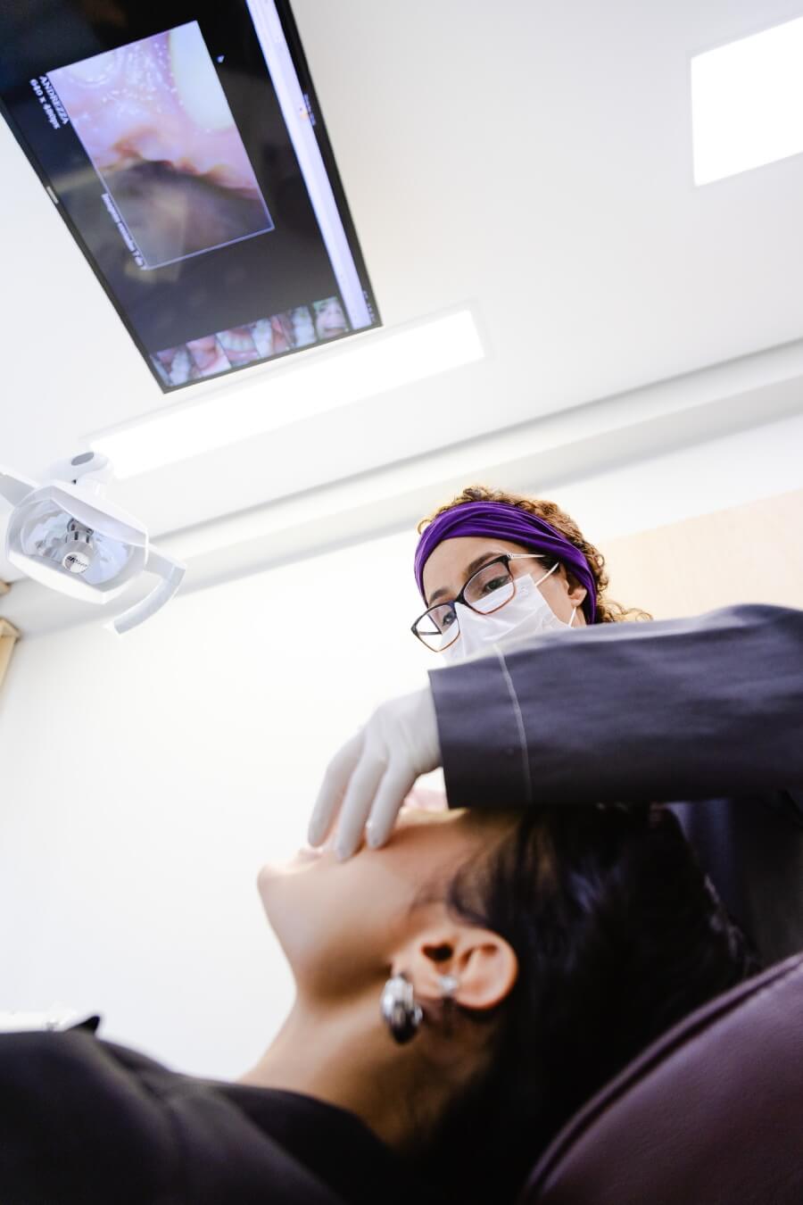 Dentista especialista em canal realizando procedimento com auxílio de monitor digital. Tratamento de canal humanizado na Vila Clementino na RM Odontologia.